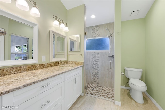 bathroom featuring vanity, toilet, and a tile shower