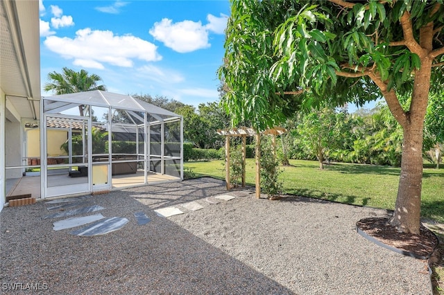 view of yard featuring glass enclosure and a patio