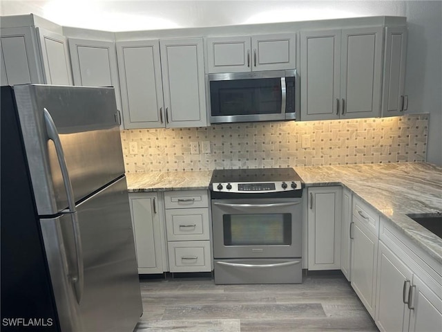 17658 Osprey Inlet Ct W, Fort Myers, FL 33908 - kitchen featuring stainless steel appliances, light stone countertops, light wood-type flooring, and tasteful backsplash