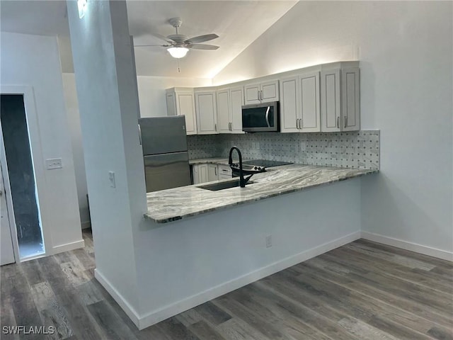 kitchen with light stone countertops, dark hardwood / wood-style flooring, refrigerator, backsplash, and sink