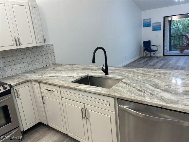 kitchen featuring stainless steel appliances, light stone counters, white cabinetry, and sink