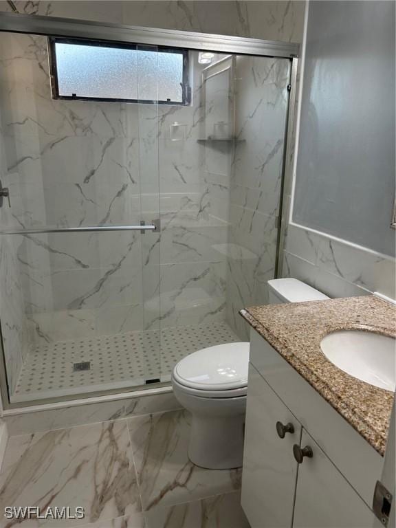 bathroom featuring vanity, toilet, a shower with shower door, and tile walls