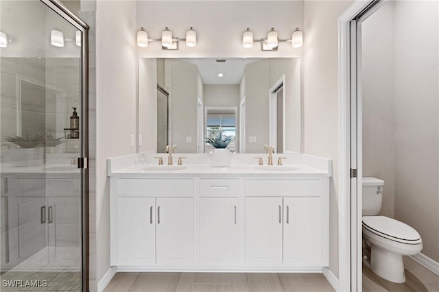 bathroom featuring hardwood / wood-style floors, vanity, toilet, and a shower with shower door