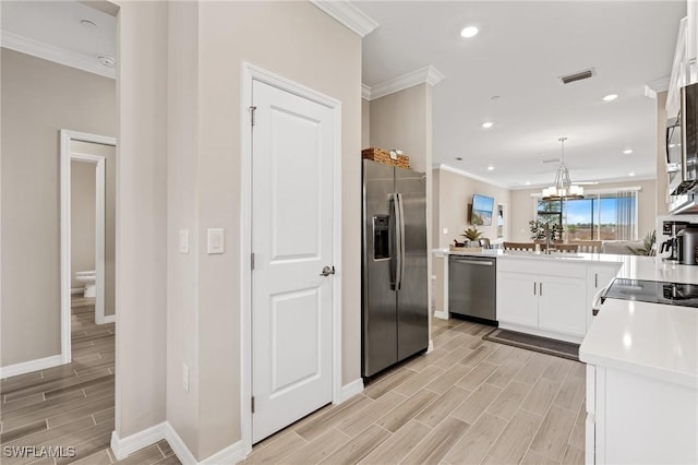 kitchen featuring an inviting chandelier, kitchen peninsula, appliances with stainless steel finishes, decorative light fixtures, and white cabinetry