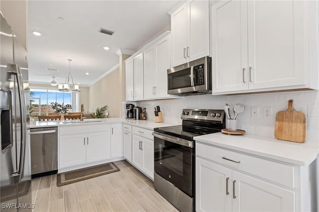 kitchen with backsplash, crown molding, sink, appliances with stainless steel finishes, and white cabinetry