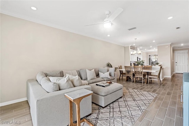 living room featuring hardwood / wood-style flooring, ceiling fan with notable chandelier, and ornamental molding