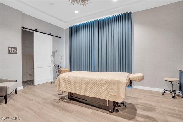 bedroom with light hardwood / wood-style floors and a barn door