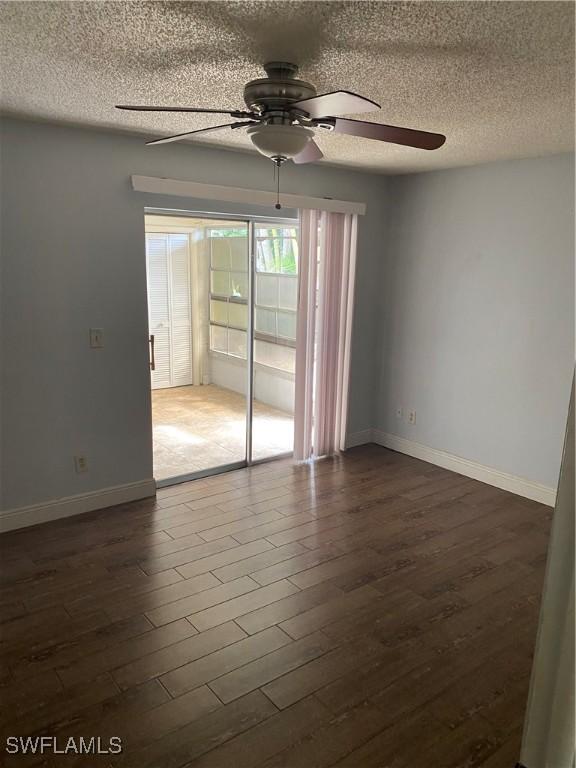 spare room with a textured ceiling, ceiling fan, and dark wood-type flooring