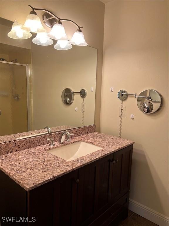 bathroom featuring a shower with door and vanity