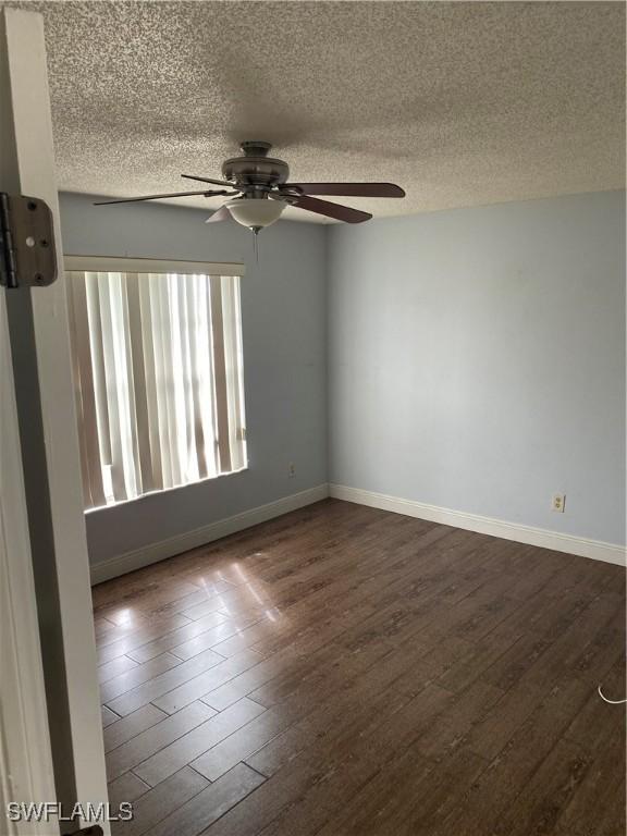 unfurnished room with a textured ceiling, ceiling fan, and dark wood-type flooring