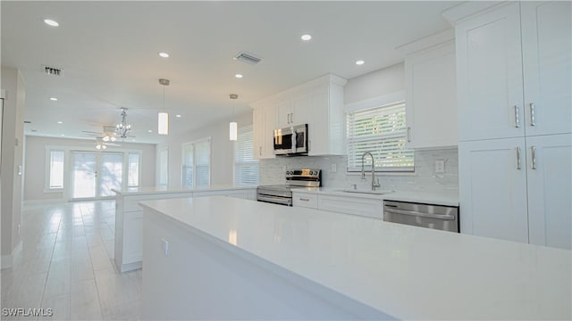 kitchen featuring visible vents, appliances with stainless steel finishes, light countertops, white cabinetry, and a sink