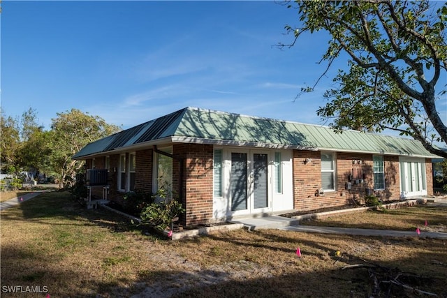 exterior space featuring a yard, metal roof, and brick siding