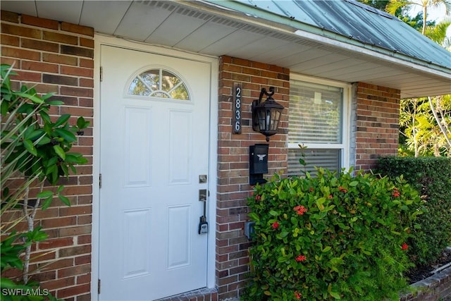 property entrance featuring metal roof, brick siding, and a standing seam roof