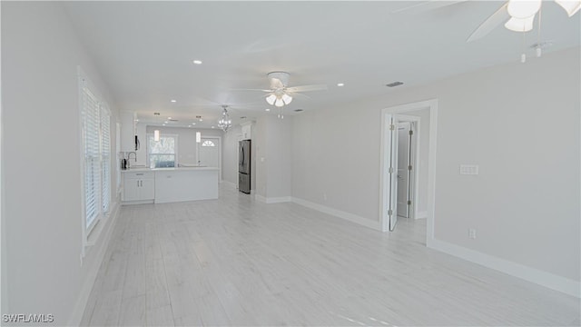 unfurnished living room with baseboards, a ceiling fan, light wood-type flooring, a sink, and recessed lighting