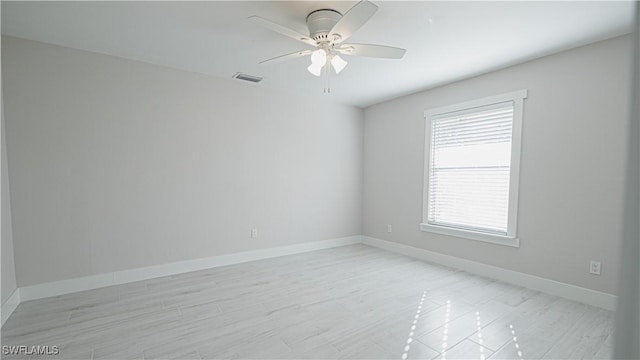 unfurnished room featuring a ceiling fan, visible vents, and baseboards