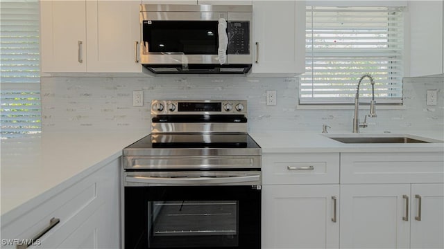 kitchen featuring a sink, white cabinetry, light countertops, appliances with stainless steel finishes, and tasteful backsplash