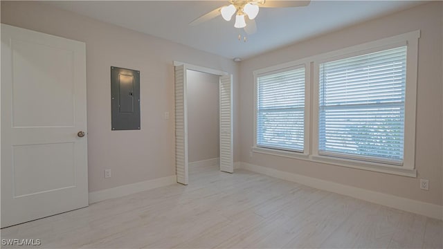 unfurnished bedroom with ceiling fan, light wood-style floors, electric panel, and baseboards