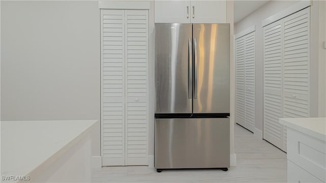 kitchen with light countertops, light wood finished floors, freestanding refrigerator, and white cabinetry