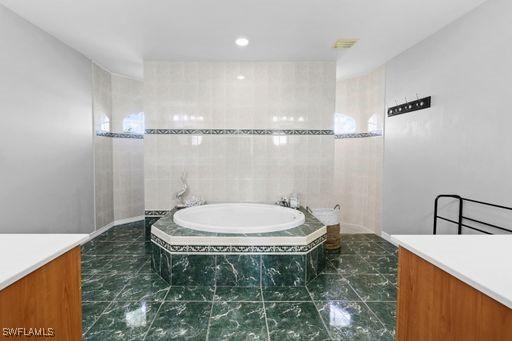 bathroom with vanity and a relaxing tiled tub