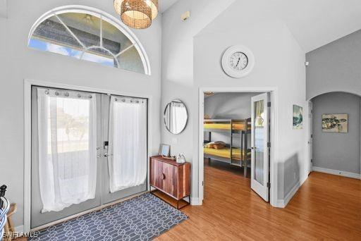 entryway with french doors, high vaulted ceiling, and wood-type flooring