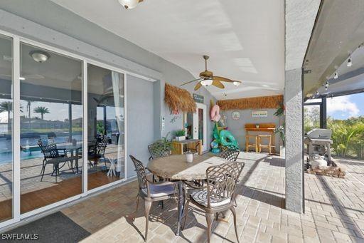 view of patio / terrace with exterior bar, ceiling fan, and a grill