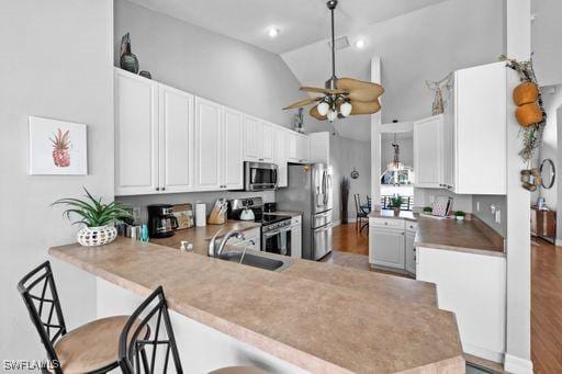 kitchen featuring white cabinetry, a kitchen bar, kitchen peninsula, and stainless steel appliances