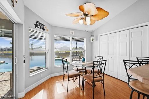 dining room featuring light hardwood / wood-style floors, vaulted ceiling, ceiling fan, and a water view