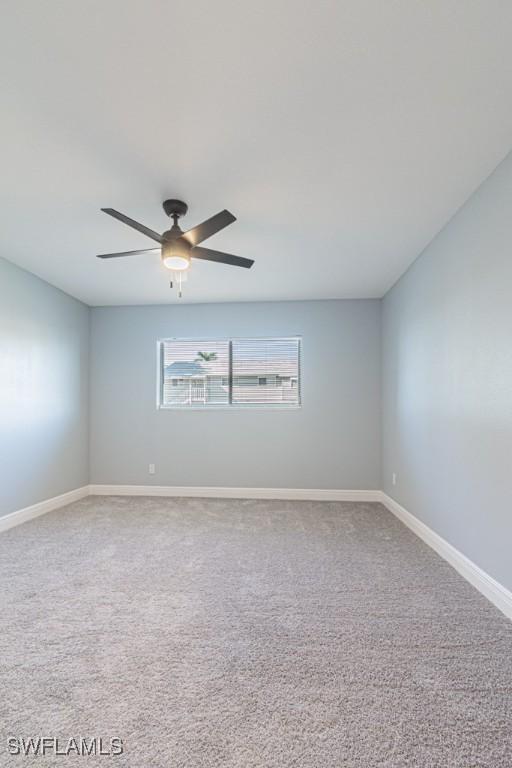 carpeted spare room featuring ceiling fan