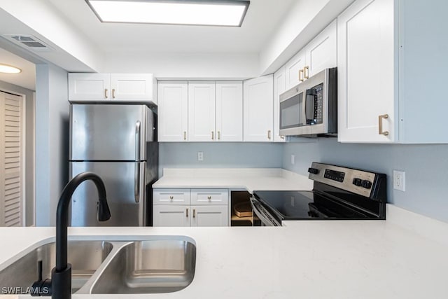 kitchen featuring appliances with stainless steel finishes, sink, and white cabinets