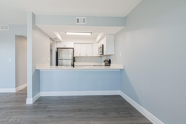 kitchen featuring sink, appliances with stainless steel finishes, white cabinetry, dark hardwood / wood-style floors, and kitchen peninsula