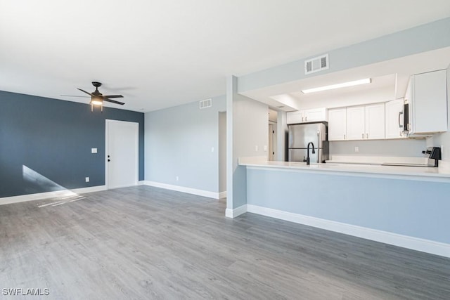 kitchen with stainless steel refrigerator, ceiling fan, range, wood-type flooring, and white cabinets