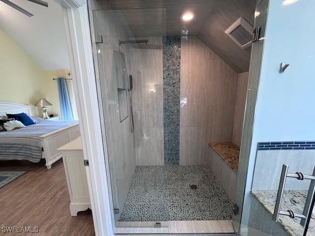 bathroom with a tile shower, lofted ceiling, and hardwood / wood-style flooring