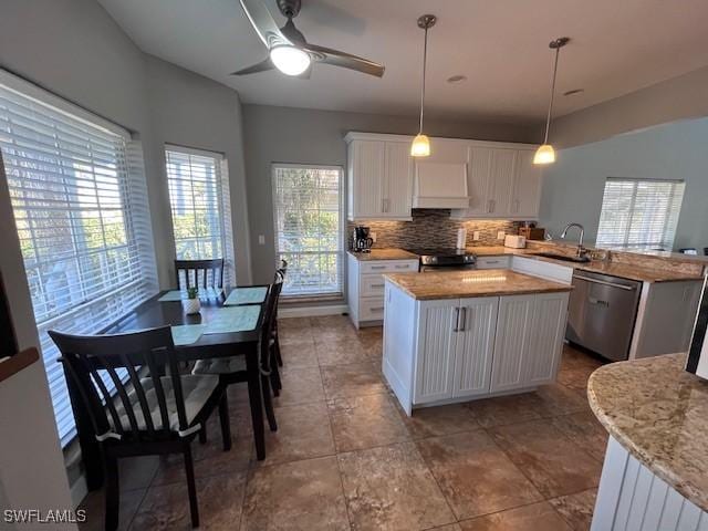 kitchen with kitchen peninsula, stainless steel dishwasher, decorative light fixtures, black range, and white cabinetry