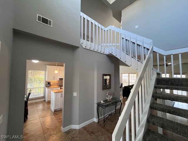 stairway featuring tile patterned flooring and a high ceiling