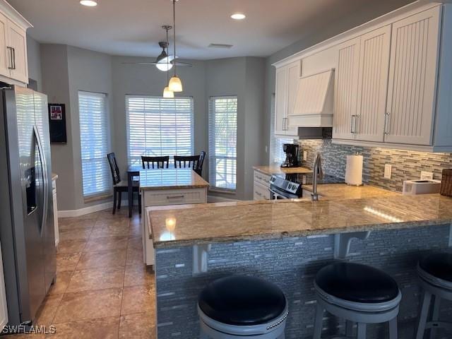 kitchen with custom exhaust hood, a breakfast bar, hanging light fixtures, appliances with stainless steel finishes, and kitchen peninsula