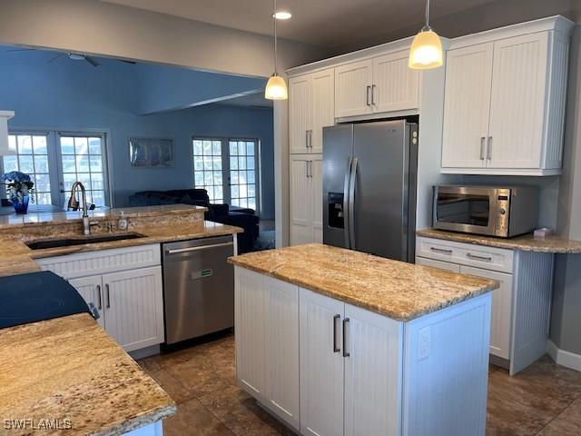 kitchen featuring white cabinets, a center island, stainless steel appliances, and sink