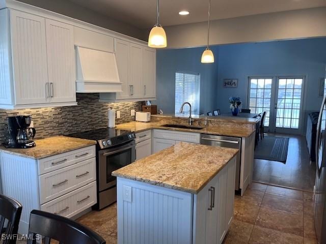 kitchen featuring white cabinetry, kitchen peninsula, decorative light fixtures, custom exhaust hood, and appliances with stainless steel finishes