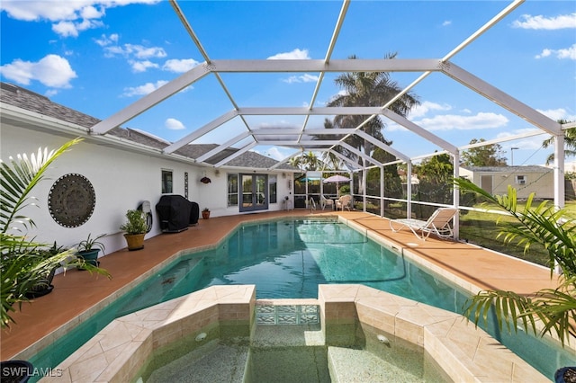 view of pool with an in ground hot tub, glass enclosure, area for grilling, and a patio area