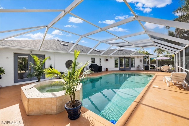 view of pool with glass enclosure, an in ground hot tub, and a patio