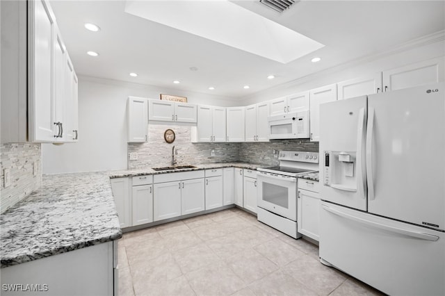 kitchen with a skylight, sink, backsplash, white appliances, and white cabinets