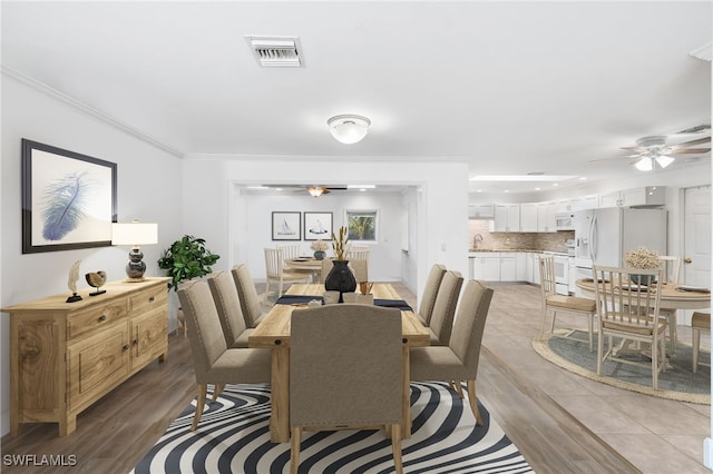 dining area with ceiling fan, ornamental molding, sink, and light hardwood / wood-style flooring