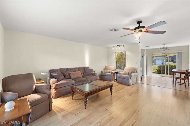 living room featuring light hardwood / wood-style floors and ceiling fan with notable chandelier