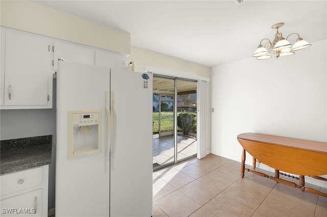 kitchen with white refrigerator with ice dispenser, pendant lighting, light tile patterned floors, an inviting chandelier, and white cabinetry