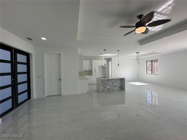 unfurnished living room featuring ceiling fan, sink, and french doors