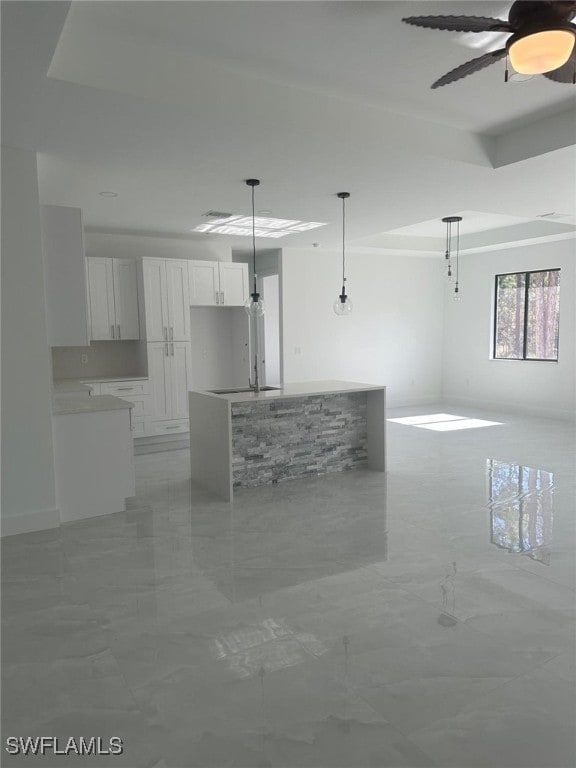 kitchen with pendant lighting, ceiling fan, a kitchen island, and white cabinetry