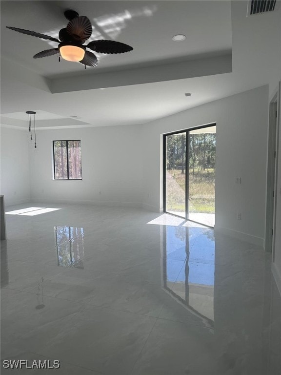 unfurnished room featuring a raised ceiling and ceiling fan