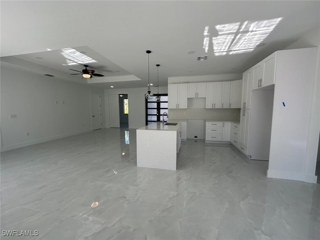 kitchen with ceiling fan, sink, a kitchen island, white refrigerator, and white cabinets