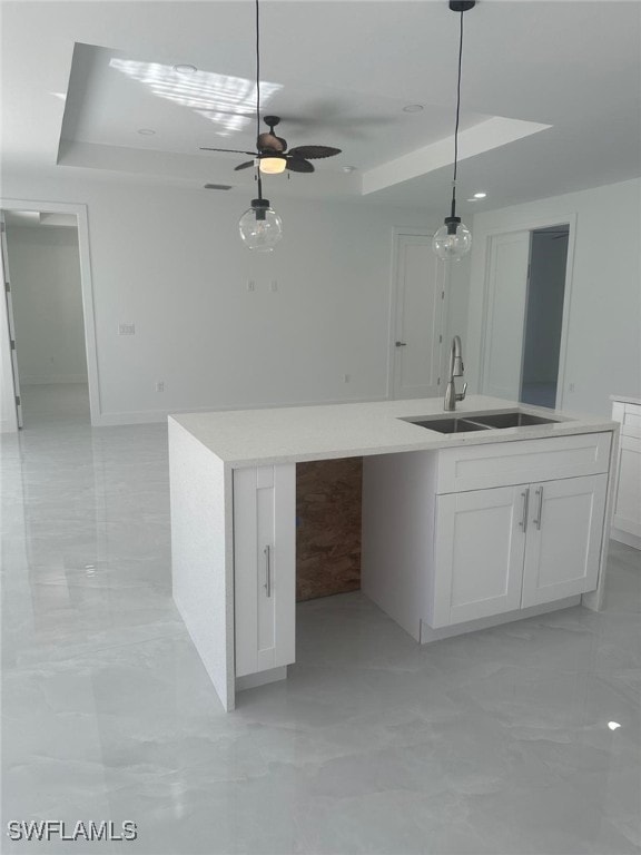 kitchen with ceiling fan, sink, an island with sink, pendant lighting, and white cabinets