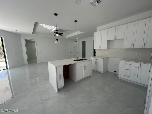 kitchen with ceiling fan, sink, white cabinetry, and a kitchen island with sink