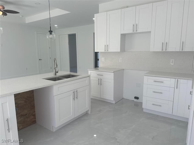 kitchen with decorative light fixtures, white cabinetry, ceiling fan, and sink